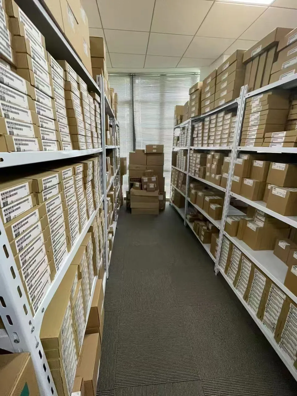 Warehouse aisle with shelves of labelled Siemens product cartons
